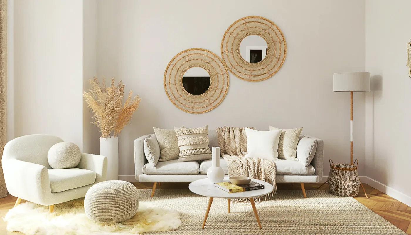 Un moderno salón en tonos neutros con un sofá blanco con cojines variados, un acogedor sillón, una mesa de centro redonda, hierba de la pampa en un jarrón, dos espejos redondos en la pared y una lámpara de pie.